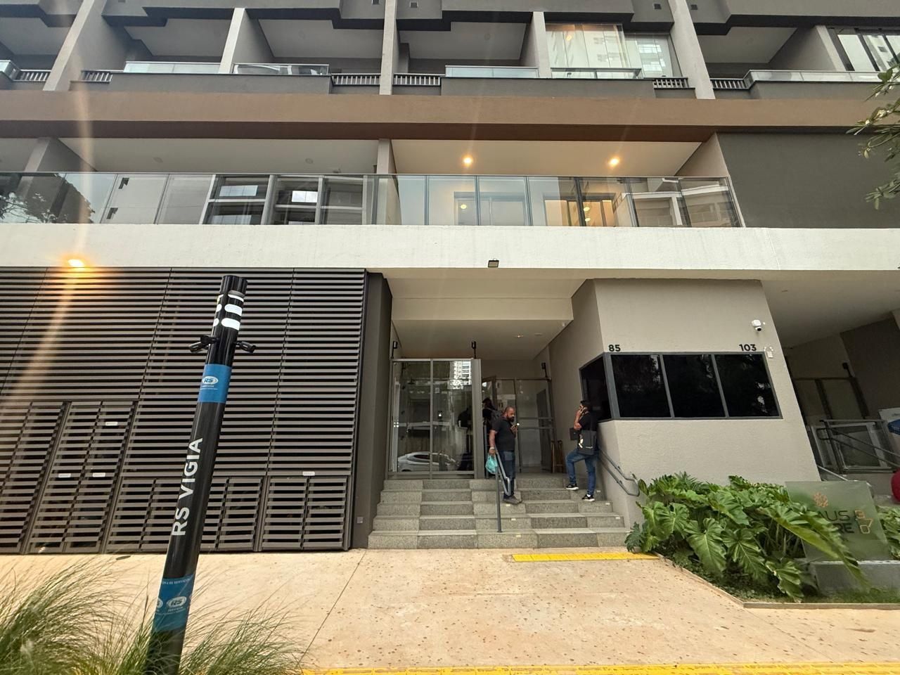 A modern building entrance with glass doors, a staircase, and a sign with numbers '85' and '103'.