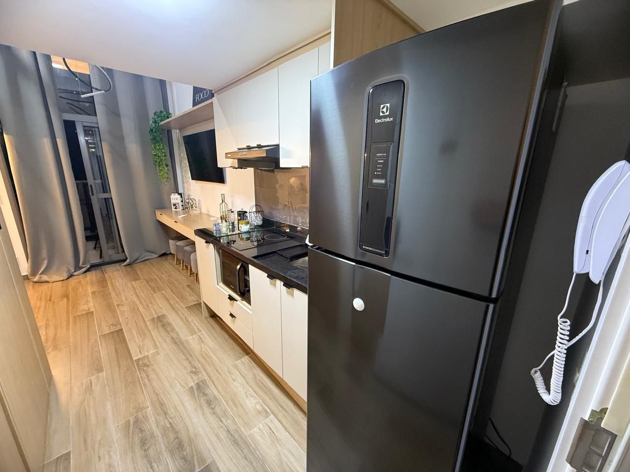 A modern kitchen with a stainless steel refrigerator, a built-in oven, and a small dining area.