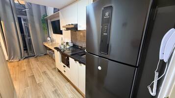 A modern kitchen with a stainless steel refrigerator, a built-in oven, and a small dining area.