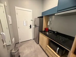 Een kleine keuken met een koelkast, een fornuis en houten kastjes.