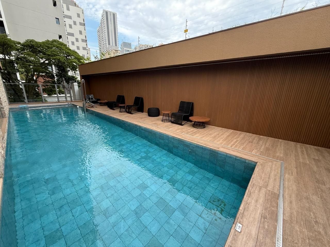 A swimming pool with a wooden deck and lounge chairs.