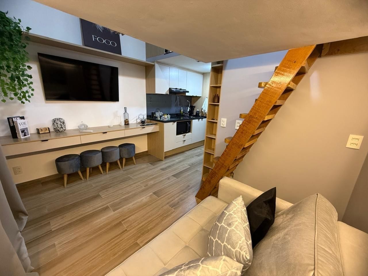 A modern living space with a kitchen, a staircase, and a sofa.