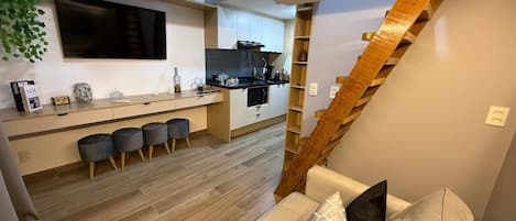 A modern living space with a kitchen, a staircase, and a sofa.