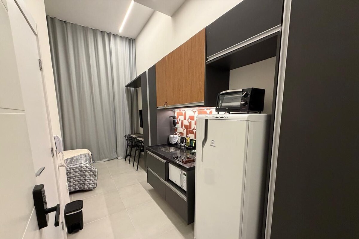 Une cuisine compacte équipée d’un réfrigérateur, d’un four à micro-ondes et d’un petit coin repas avec des chaises et une table.