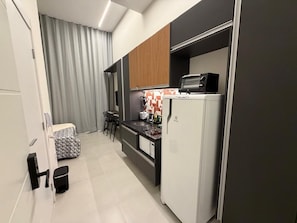 Cuina compacta amb nevera, microones i zona de dinar petita amb cadires i taula.