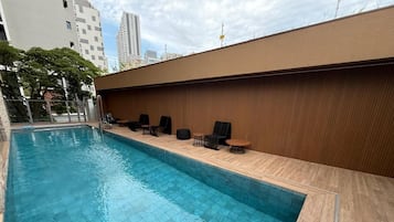 A swimming pool with a wooden deck and lounge chairs.