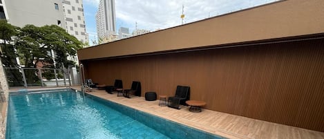 A swimming pool with a wooden deck and lounge chairs.