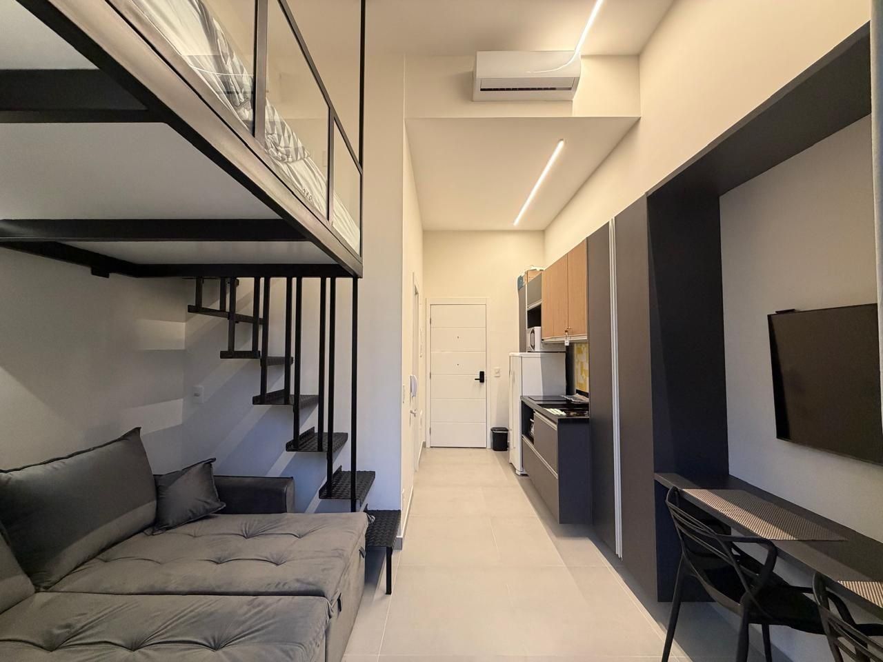 A modern interior with a sofa, a dining table, a TV, and kitchen cabinets.