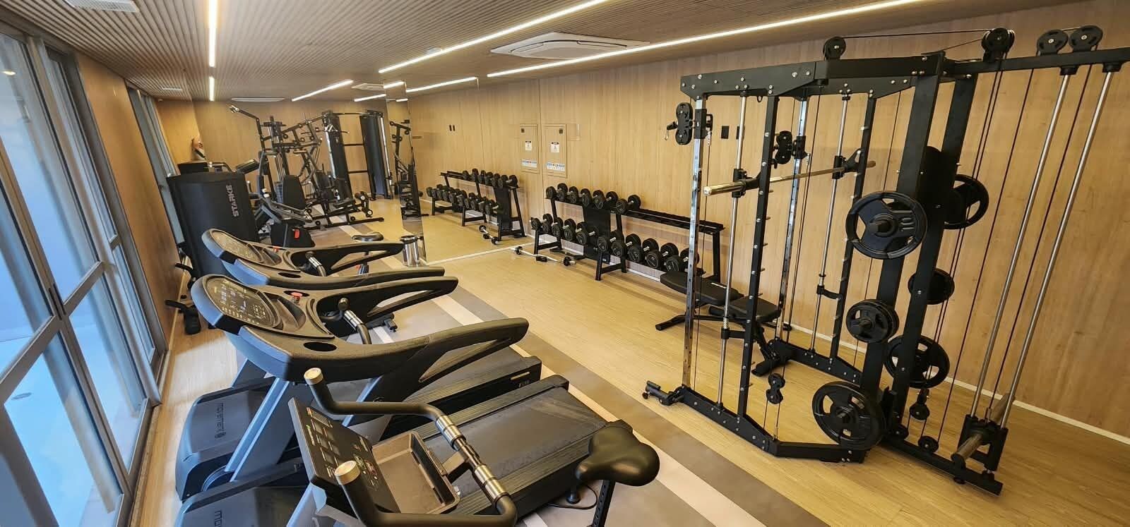 Et fitnesscenter med løbebånd, styrkemaskiner og håndvægte.