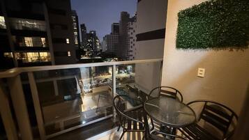 A balcony with a glass railing, a round table, and four chairs.