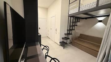 Quarto moderno com beliche, sofá, escrivaninha e cadeira, e uma escada.