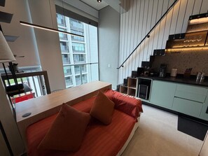 Un dormitori loft modern amb una finestra gran, una zona de cuina i una escala.