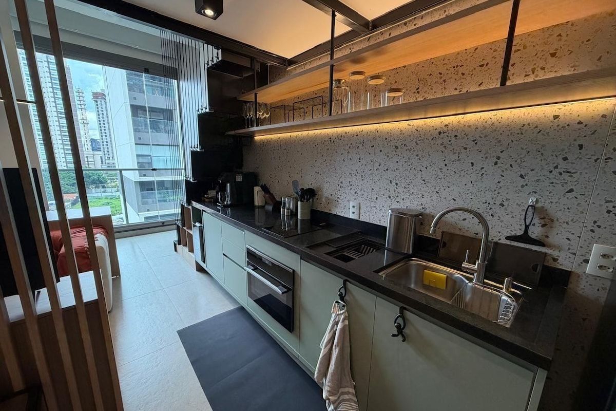 Una cocina moderna con un amplio ventanal, horno empotrado y pileta de acero inoxidable.