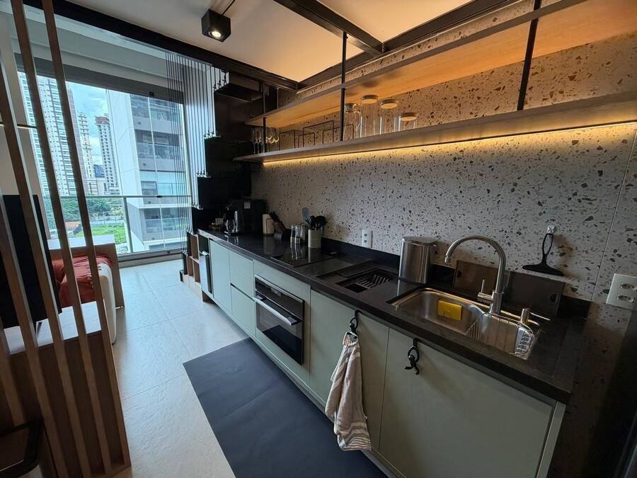 A modern kitchen with a large window, built-in oven, and stainless steel sink.