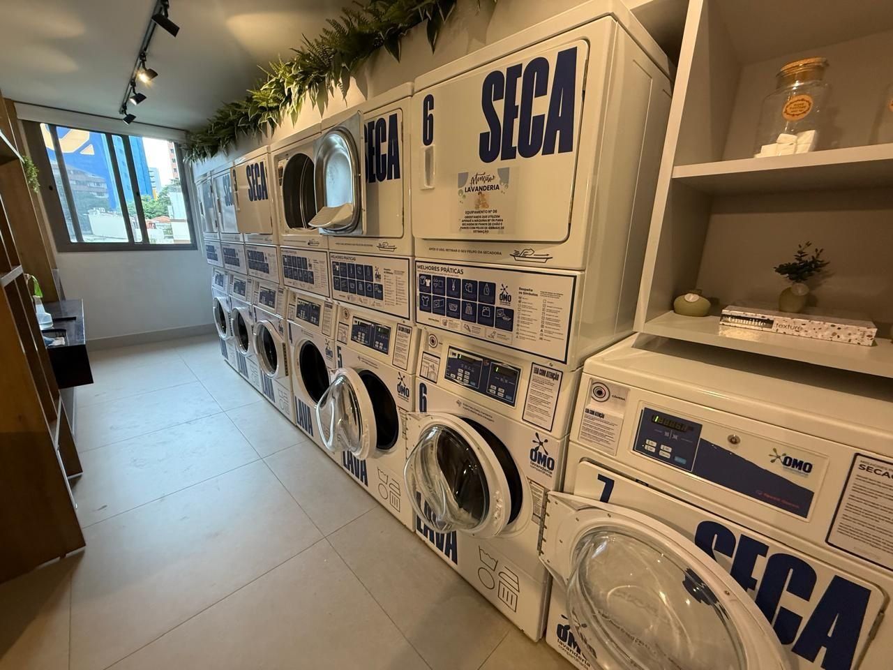 Un cuarto de lavandería con varias lavadoras, cada una etiquetada con 'SECA' y 'LAVANDERÍA'.