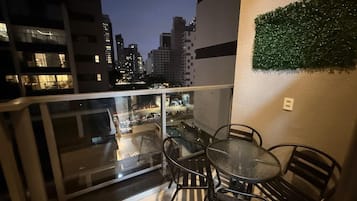 A balcony with a glass railing, a round table, and four chairs.