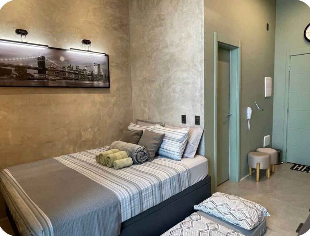 A bedroom with a bed, pillows, a wall-mounted picture, and a door.