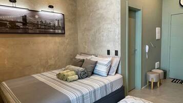 A bedroom with a bed, pillows, a wall-mounted picture, and a door.