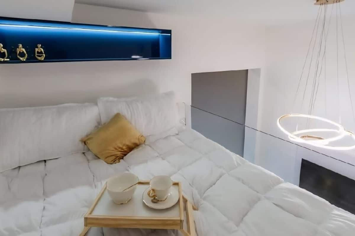 Une chambre à coucher moderne avec un lit, une table de chevet et un luminaire suspendu.