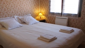 A neatly made bed with white linens and pillows, a bedside lamp, and a radiator. - La Ferme Tranquille Gîte de Groupe (Puivert)