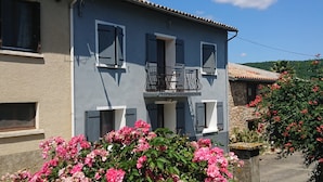 A two-story building with a balcony, a window with shutters, and a flower box with pink flowers. - La Ferme Tranquille Gîte de Groupe (Puivert)