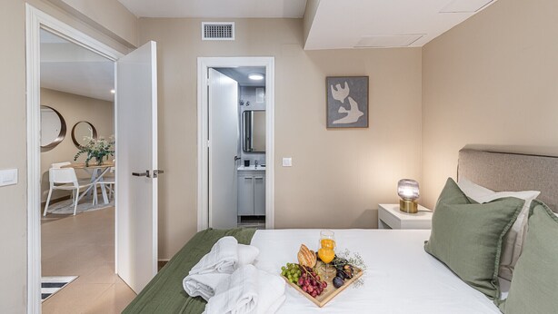 A hotel room with a bed, a breakfast tray, a nightstand, and a bathroom visible through an open door. - Waou Seville Center I (Sevilla)