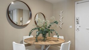 A dining area with a round wooden table, white chairs, two wall-mounted mirrors, and a decorative plant arrangement. - Waou Seville Center I (Sevilla)