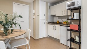 A compact kitchen with white cabinets, a microwave, and a fruit bowl on the counter. - Waou Seville Center I (Sevilla)