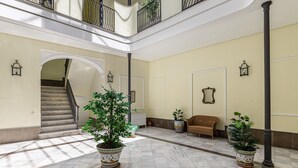 Un'ampia zona interna con pavimento in marmo, una scala e un balcone con ringhiere in metallo.