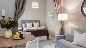 A hotel room with a bed, bedside table, lamp, and a round table with a fruit bowl. - Waou Seville Center III (Sevilla)