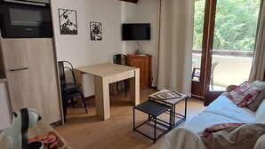 A compact living space with a kitchenette, a dining area, a sofa, and a TV.