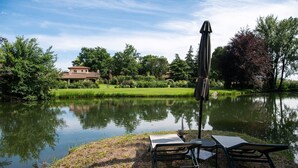 Un entorno tranquilo junto al lago, con un pabellón, una mesa y una silla cerca del agua.