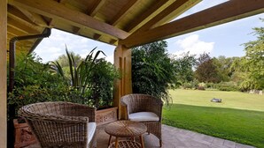Une terrasse couverte avec des meubles en osier, une pelouse et un chemin en pierre.