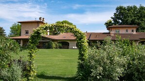 Une grande maison avec une pelouse bien entretenue, un patio couvert et une arche de jardin.