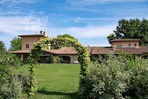 A large house with a well-maintained lawn, a covered patio, and a garden archway.