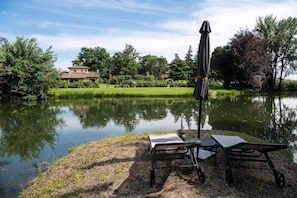 A tranquil lakeside setting with a gazebo, a table, and a chair by the water.