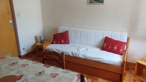 Un dormitorio con una cama de madera, una mesita de noche, una lámpara y un cuadro colgado en la pared.