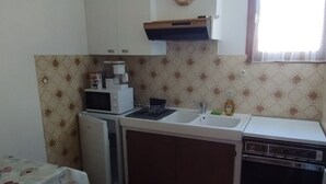 Una cocina compacta con microondas, fregadero y estufa.