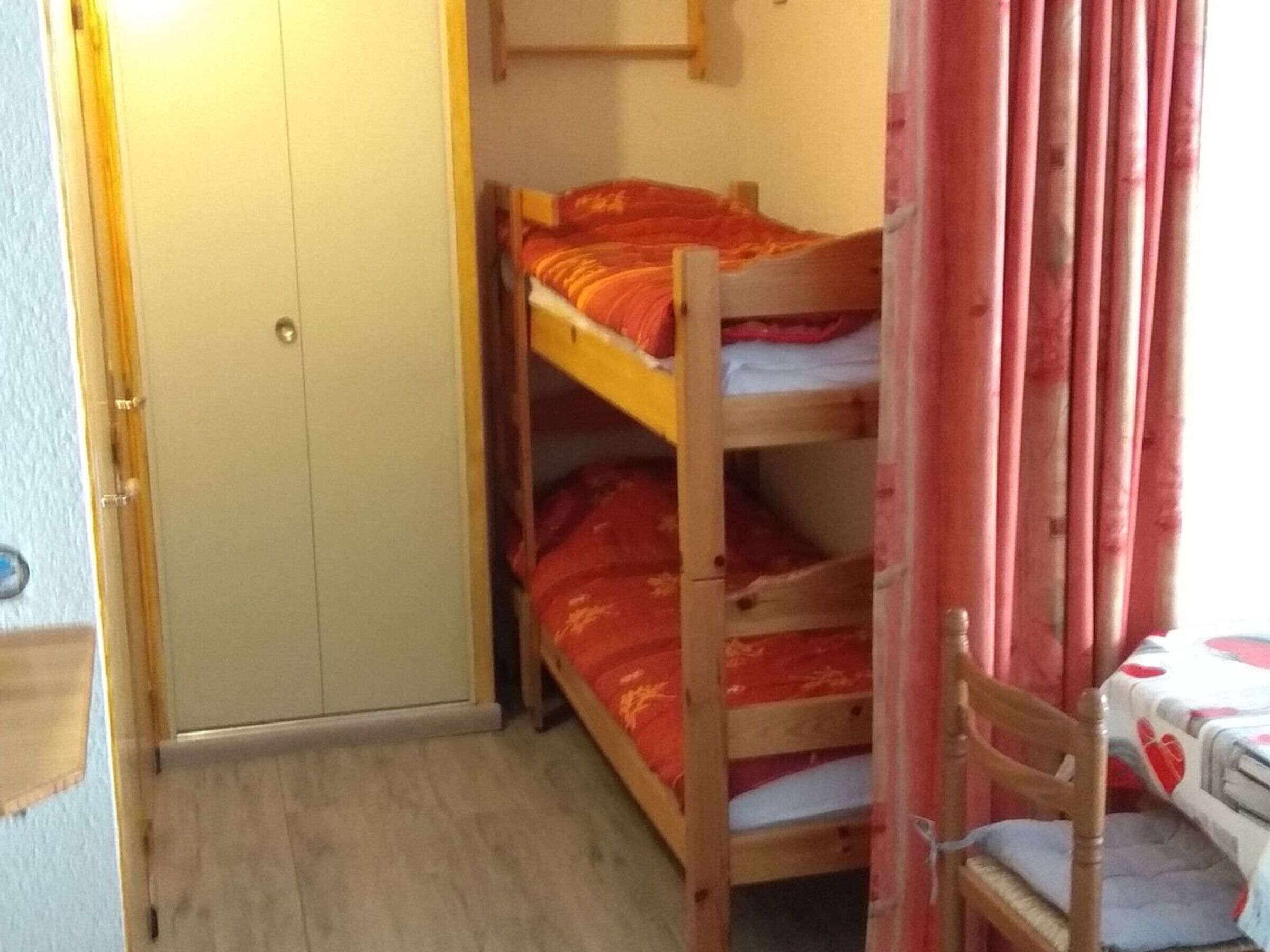 Dormitorio con literas, un armario de madera y una silla.