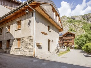 A two-story building with a stone facade, wooden balconies, and a mountain backdrop. - 3-room apartment for 6 with parking and Wifi in Valloire (Valloire)