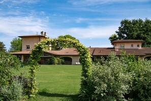 Une grande maison avec une pelouse bien entretenue, un patio couvert et une arche de jardin.