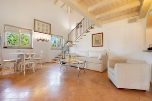 Un grand espace de vie comprenant une table à manger, des chaises, un canapé et un escalier.
