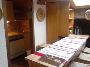 A kitchen with wooden cabinets, a sink, and a countertop. There is a table with a placemat and a picture of a cat.