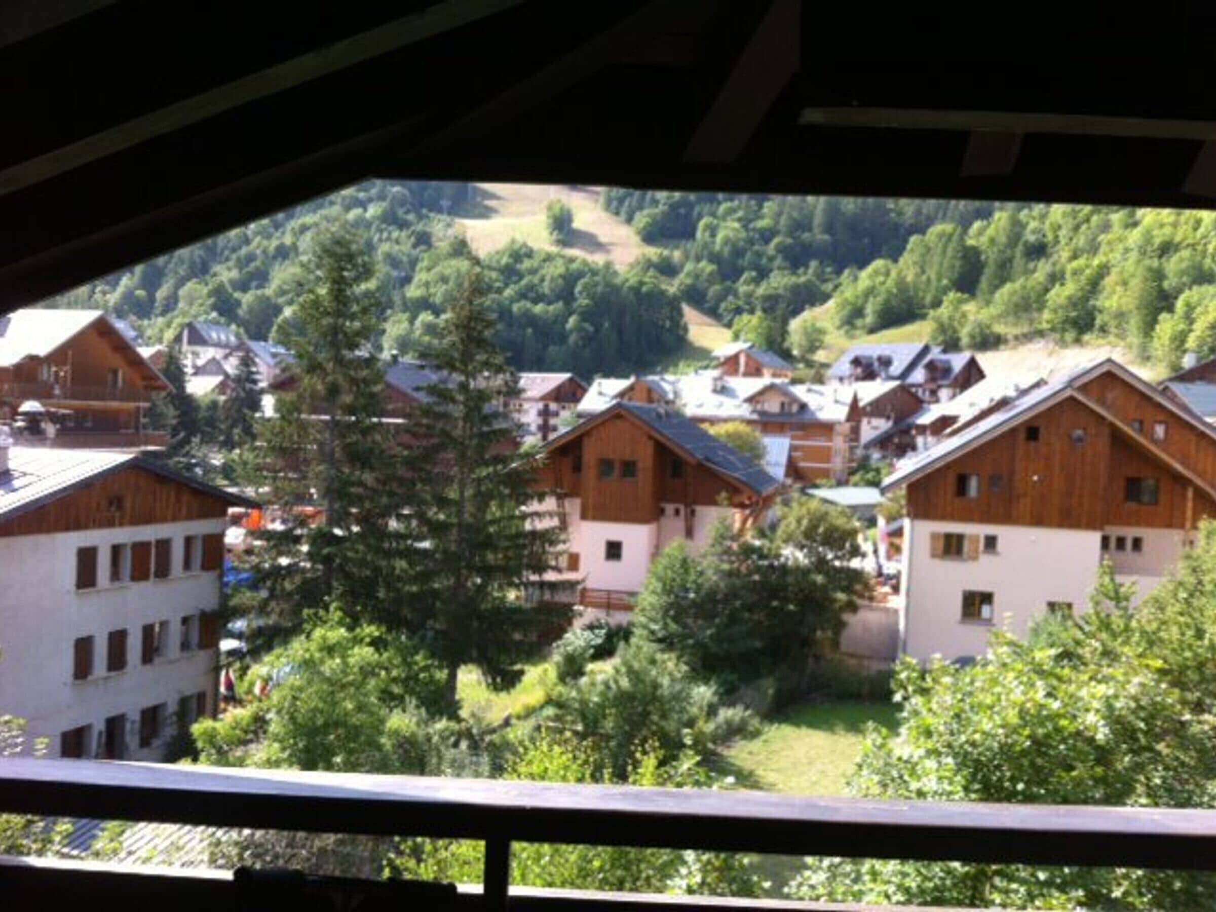 A view of a mountain village with wooden houses and a forested backdrop.