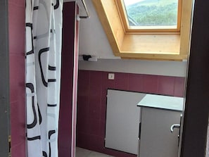 A room with a skylight, a white cabinet, and a patterned curtain.