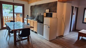 A modern kitchen with wooden cabinets, a dining table, and a view of the outside.