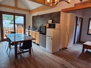A modern kitchen with wooden cabinets, a dining table, and a view of the outside.