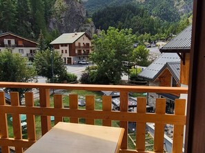 Ein Balkon mit Holzgeländer mit Blick auf eine Wohngegend, mit Häusern und einem Berg im Hintergrund.