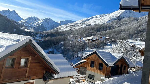 A mountain lodge with wooden cabins, snow-covered roofs, and a view of snow-capped mountains. - Chalet for 8 facing south, terrace, private parking (Valloire)