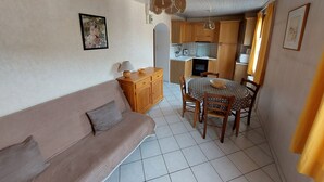 A cozy living area with a sofa, dining table, and kitchen in the background. - Spacious 2-room for 4 people, pets allowed (Valloire)